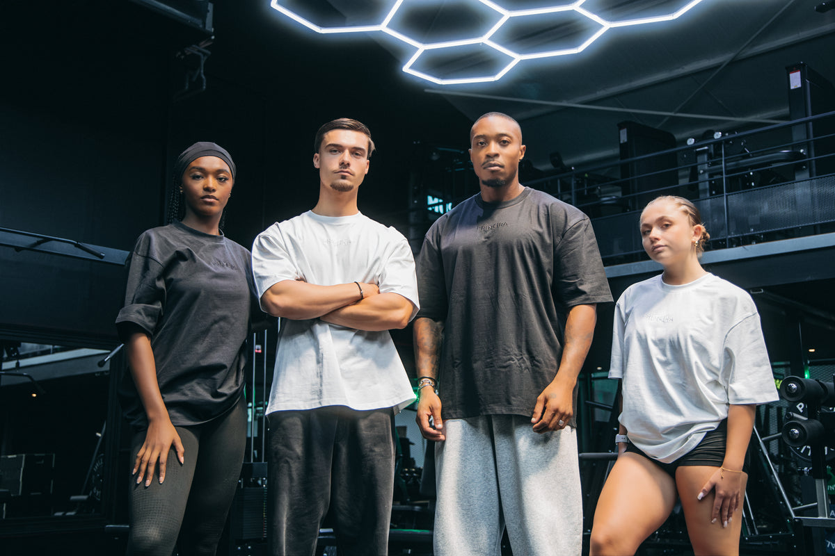 T-shirts oversize Primeira Fitness portés par quatre athlètes en salle de sport